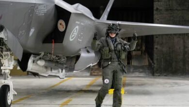İzlanda'daki Keflavik Hava Üssü'ndeki bir hangarda park edilmiş bir Norveç F-35 savaş uçağının yanında bir pilot